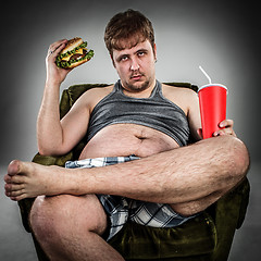 Image showing Fat man eating hamburger