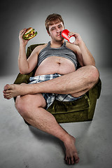 Image showing Fat man eating hamburger