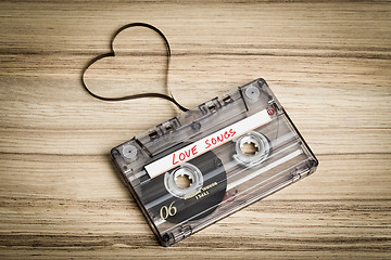 Image showing Audio cassette tape on wooden backgound. Film shaping heart