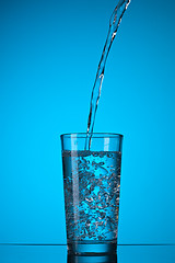 Image showing water pouring into glass on blue