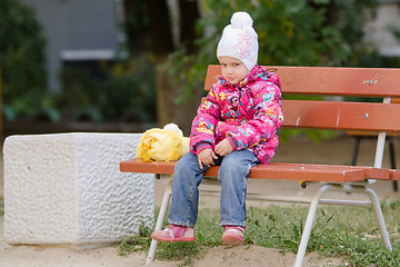 Image showing Gloomy girl in autumn clothes sitting on a bench