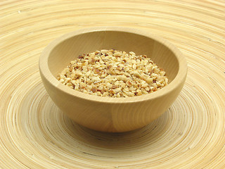 Image showing Wooden bowl with roasted hazelnuts on bamboo plate