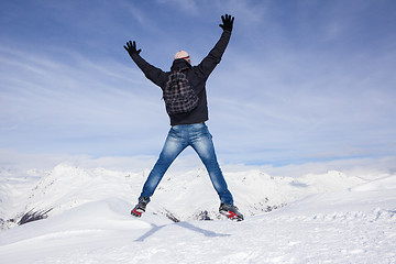 Image showing Young man jumps for joy in the snowy mountains