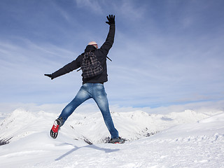 Image showing Young man jumps for joy in the snowy mountains