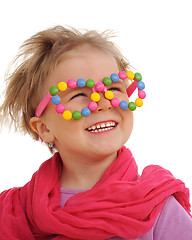 Image showing Portrait of cute little girl wearing funny glasses, decorated with colorful sweets, smarties, candies