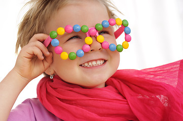 Image showing Portrait of cute little girl wearing funny glasses, decorated with colorful sweets, smarties, candies