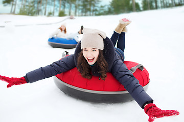 Image showing group of happy friends sliding down on snow tubes