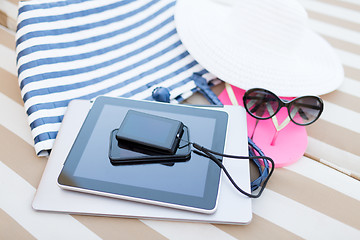 Image showing close up of tablet pc and smartphone on beach