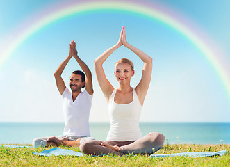 Image showing smiling couple making yoga exercises outdoors