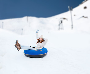 Image showing happy teenage girl sliding down on snow tube