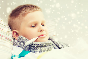 Image showing ill boy with thermometer lying in bed at home