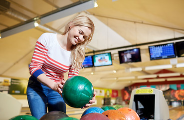Image showing happy young woman holding ball in bowling club