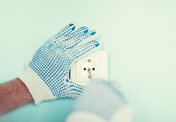 Image showing close up of male in gloves installing new socket