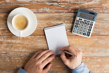 Image showing close up of hands with calculator and notebook