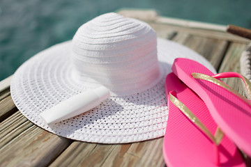Image showing close up of hat, sunscreen and slippers at seaside