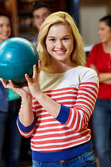 Image showing happy young woman holding ball in bowling club