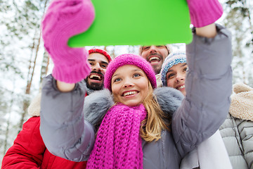 Image showing smiling friends with tablet pc in winter forest