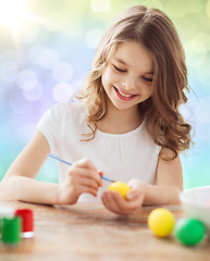 Image showing happy girl with brush coloring easter eggs