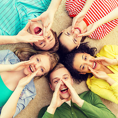 Image showing smiling people lying down on floor and screaming