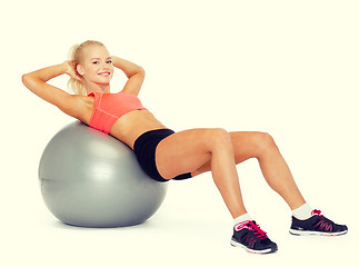 Image showing smiling sporty woman exercising on fitness ball