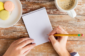 Image showing close up of hands, notebook, coffee and cookies