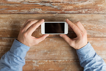 Image showing close up of male hands with smartphone on table