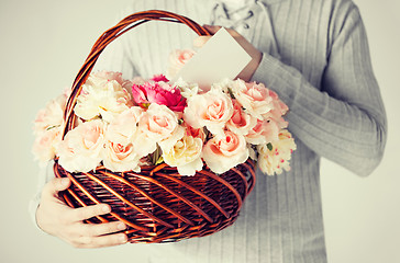 Image showing man holding basket full of flowers and postcard