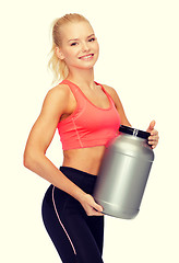 Image showing smiling sporty woman with jar of protein