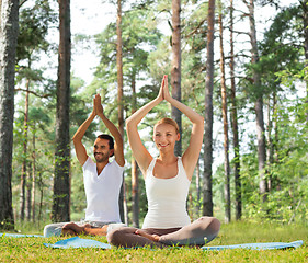 Image showing smiling couple making yoga exercises outdoors