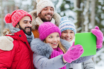 Image showing smiling friends with tablet pc in winter forest