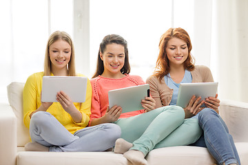 Image showing three smiling teenage girls with tablet pc at home