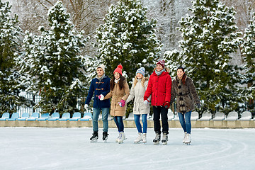 Image showing happy friends ice skating on rink outdoors