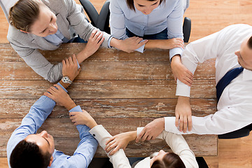 Image showing close up of business team holding hands at table