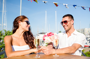 Image showing smiling couple with bunch and champagne at cafe