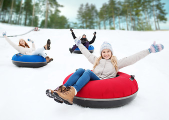 Image showing group of happy friends sliding down on snow tubes