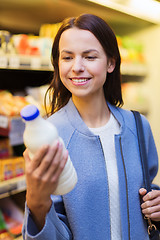 Image showing happy woman holding milk bottle in market