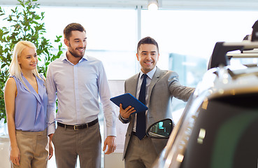 Image showing happy couple with car dealer in auto show or salon