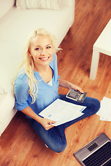 Image showing smiling woman with papers, laptop and calculator