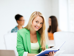 Image showing smiling student girl reading book at school