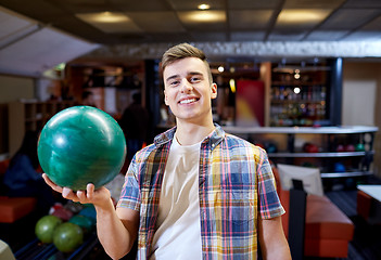 Image showing happy young man holding ball in bowling club