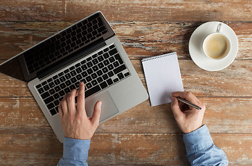 Image showing close up of male hands with laptop and notebook