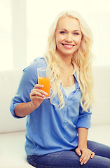 Image showing smiling woman with glass of orange juice at home