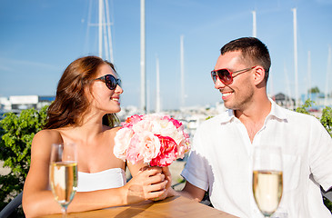 Image showing smiling couple with bunch and champagne at cafe