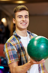 Image showing happy young man holding ball in bowling club