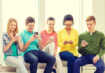 Image showing smiling students with smartphone texting at school