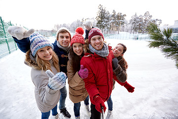 Image showing happy friends with smartphone on ice skating rink