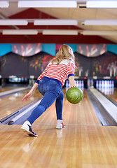 Image showing happy young woman throwing ball in bowling club