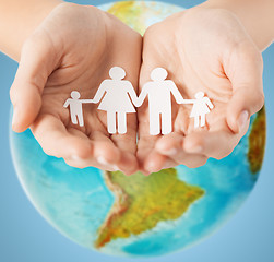 Image showing human hands holding paper family over earth globe