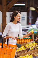 Image showing happy young woman with food basket in market