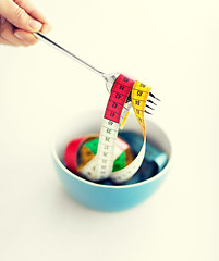 Image showing woman hand with fork, bowl and measuring tape